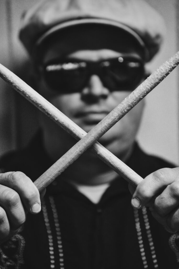 Portrait eines Musiker mit Drumsticks vorm Gesicht