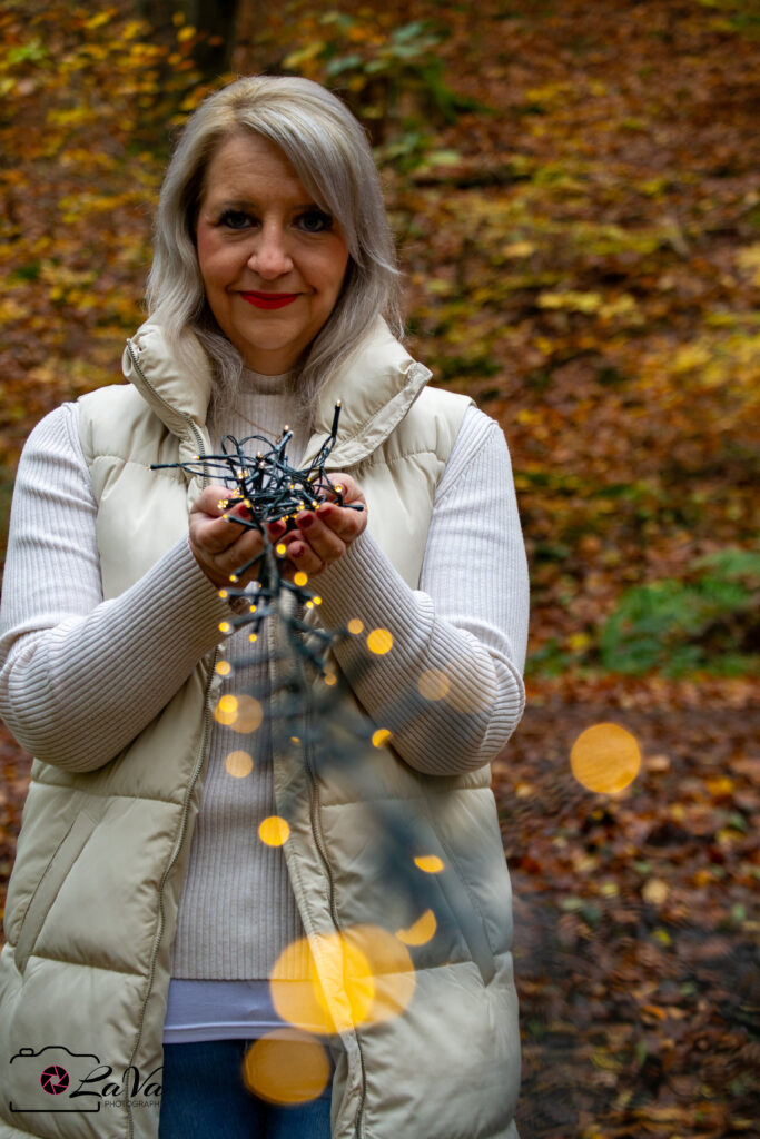 Blonde Frau im Wald mit Lichterkette in der Hand