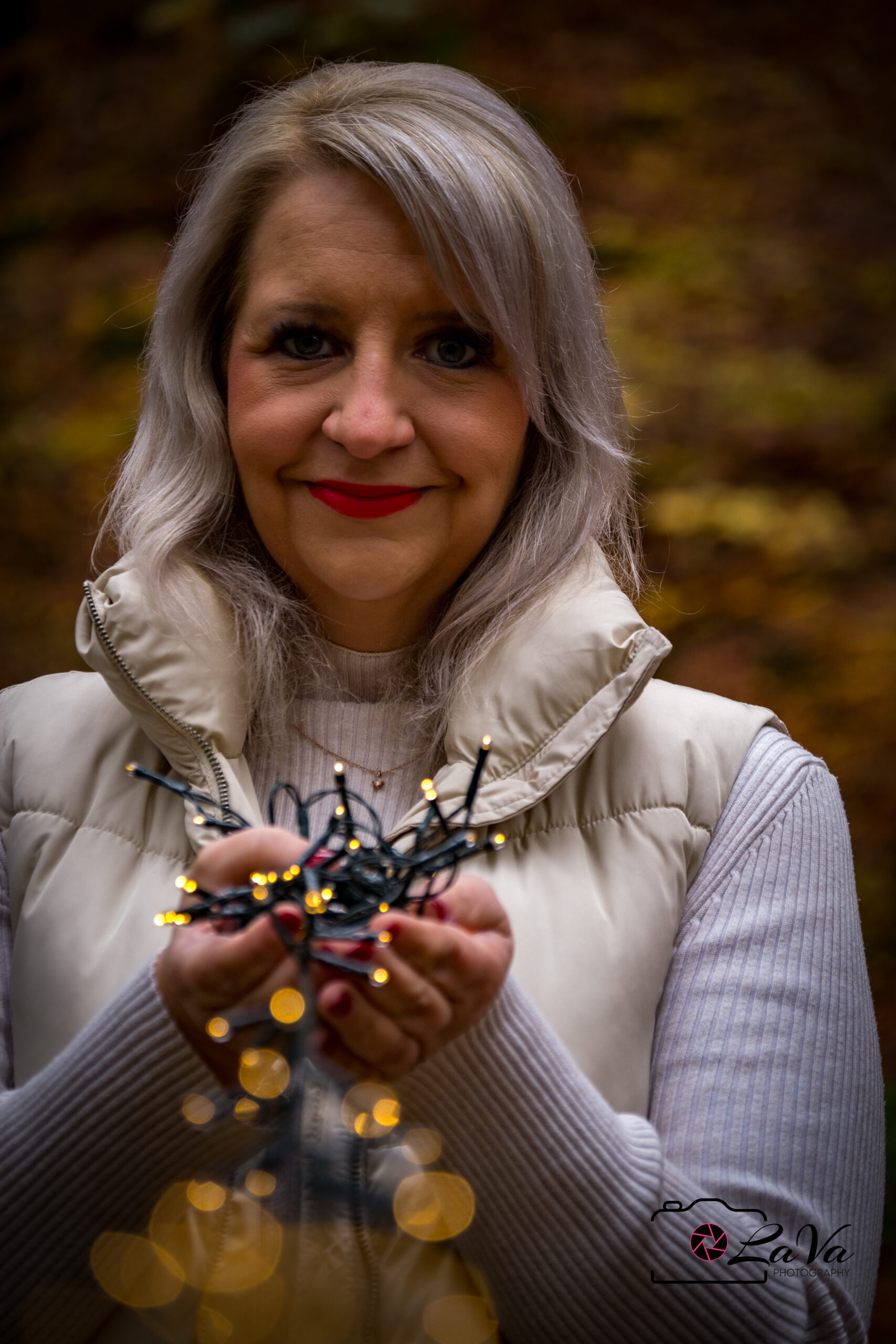Blonde Frau blickt in die Kamera mit einer Lichterkette in der Hand