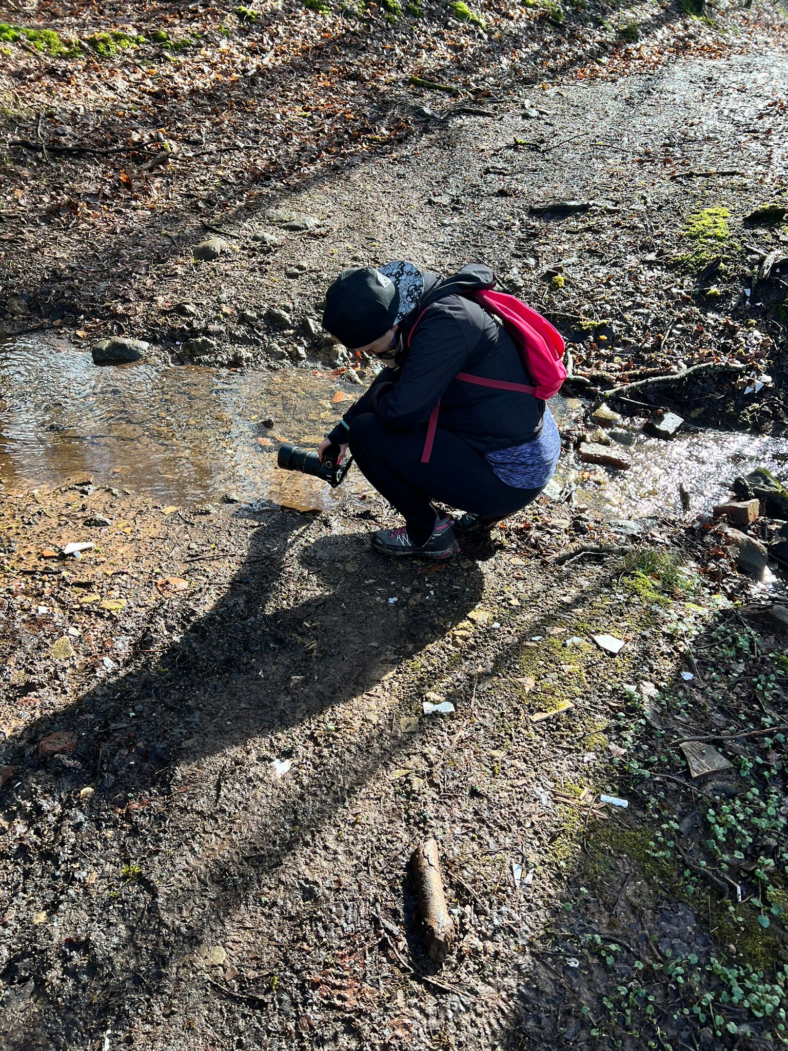 Fotografin in Action in der Hocke und fotografiert über dem Boden