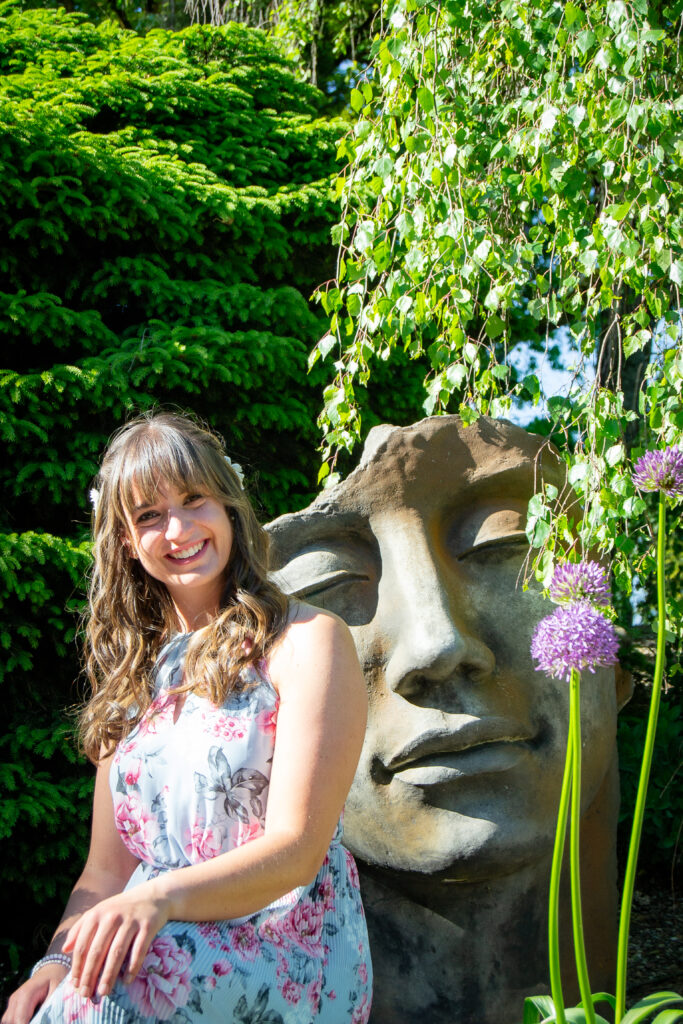 Brünette Frau neben einer Statue und Blumen